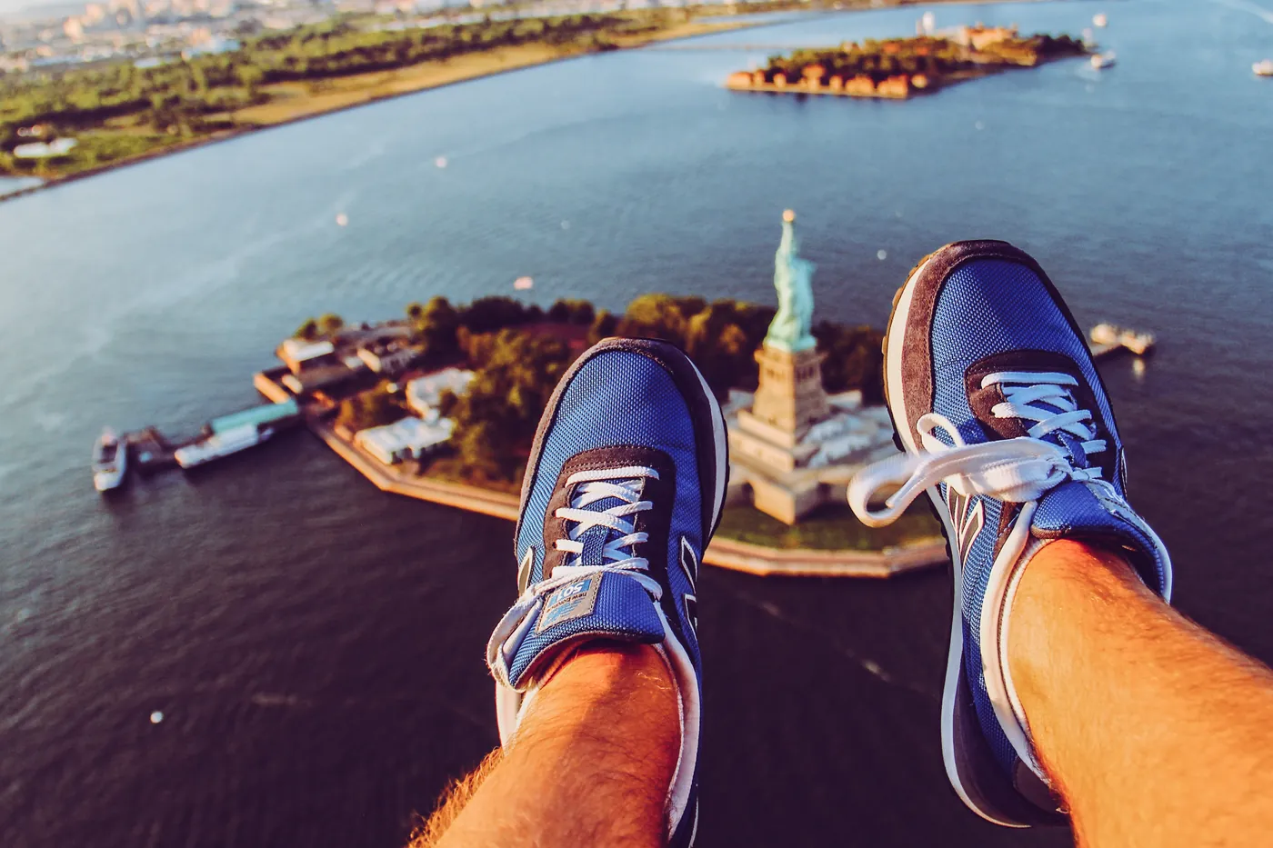 Doors-off helicopter cabin in flight over New York with photographer feet visible.